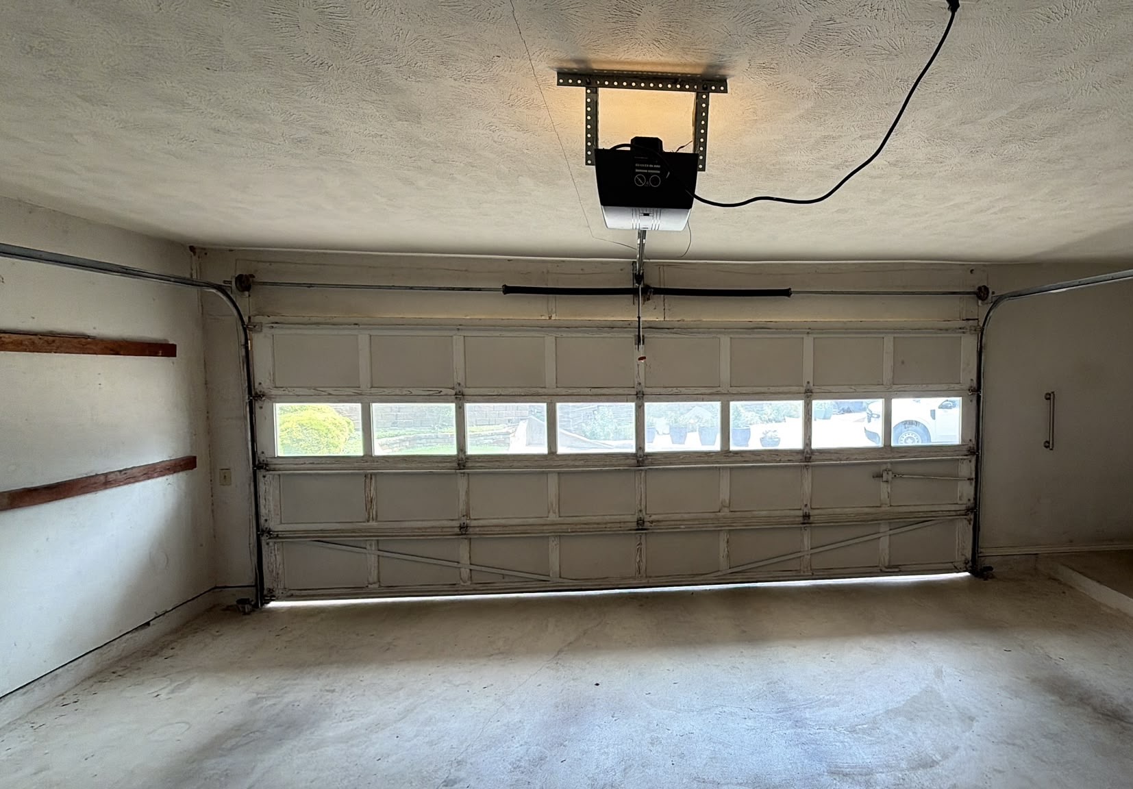 Garage interior with new belt-drive opener mounted to the ceiling above a windowed door