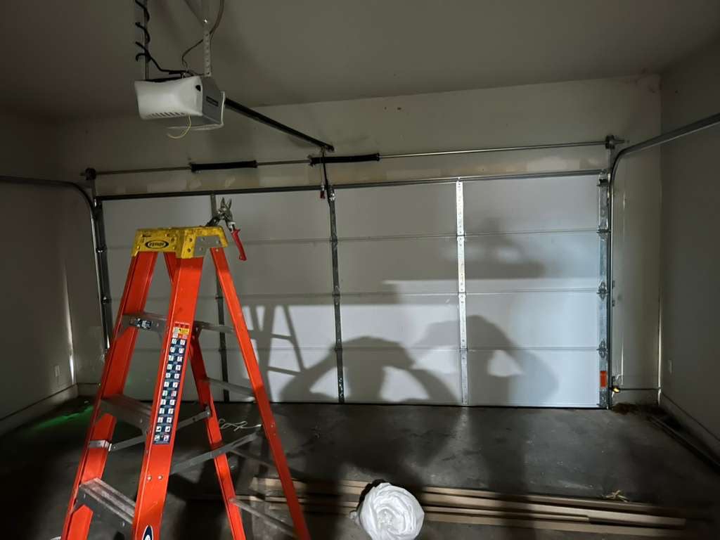 Garage door with new springs, cables, and opener rail during a night service call