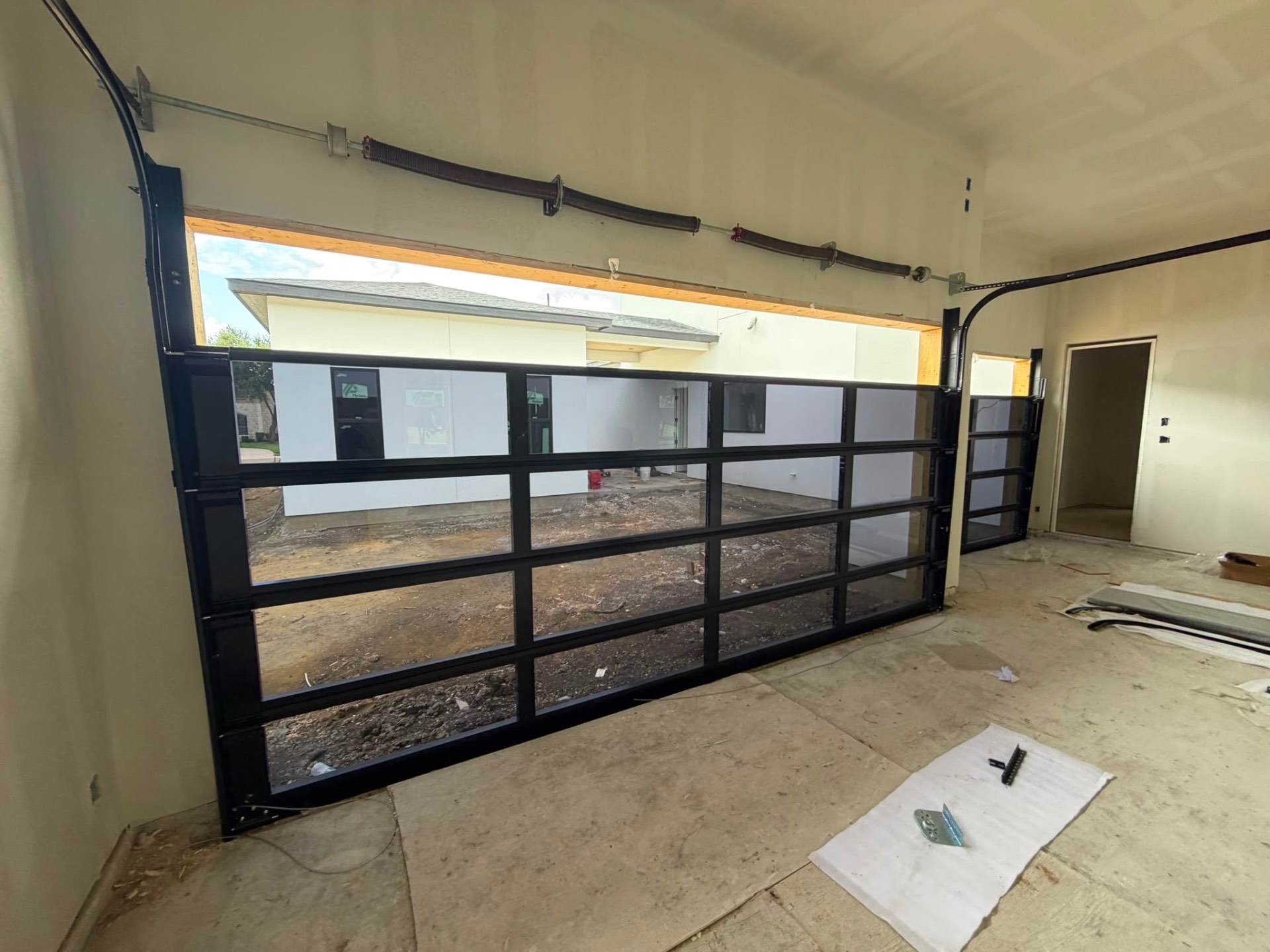 Full-view black aluminum and glass garage door installed in a new build garage