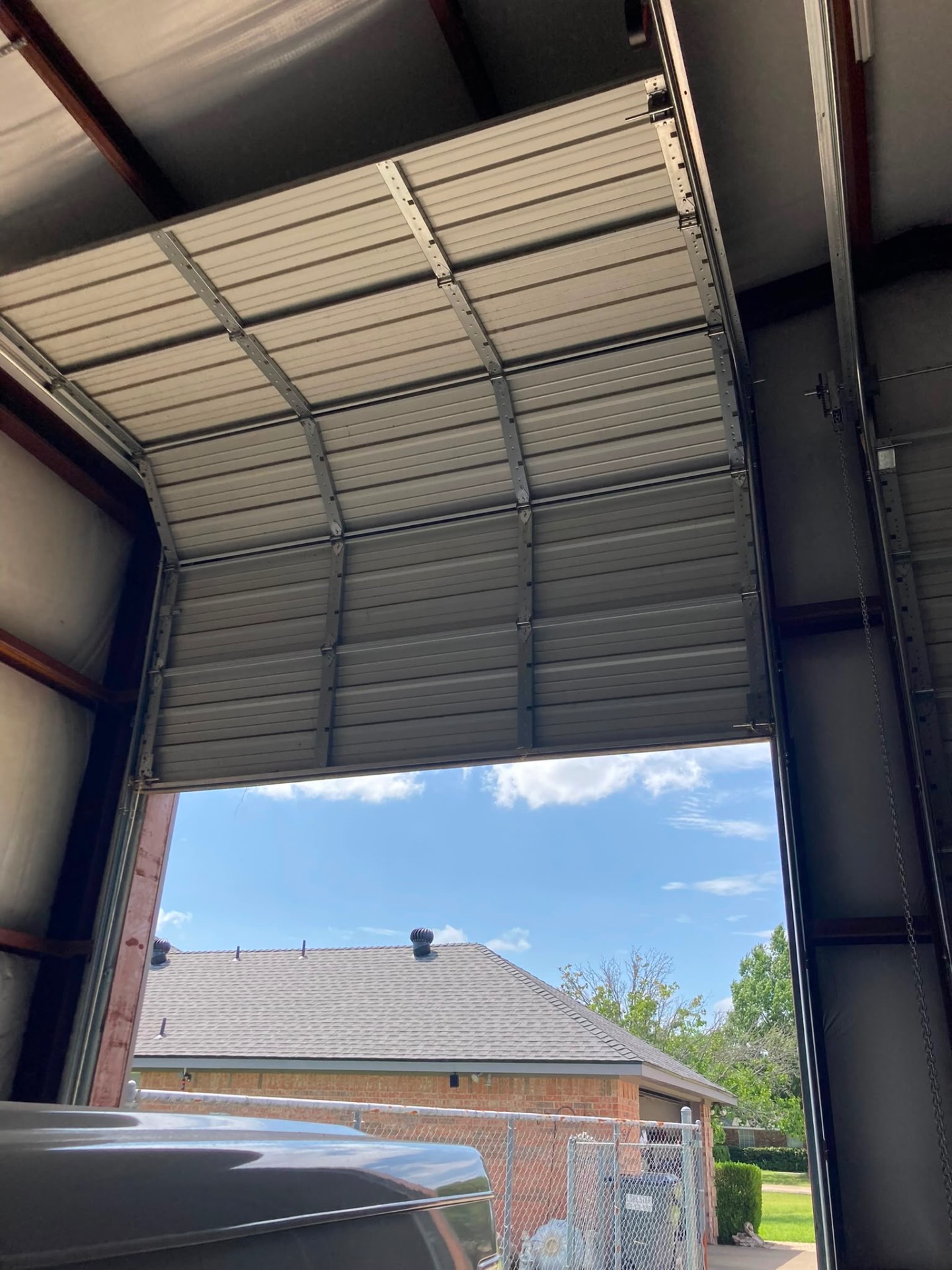 Tall commercial garage door on high-lift track inside a metal shop building